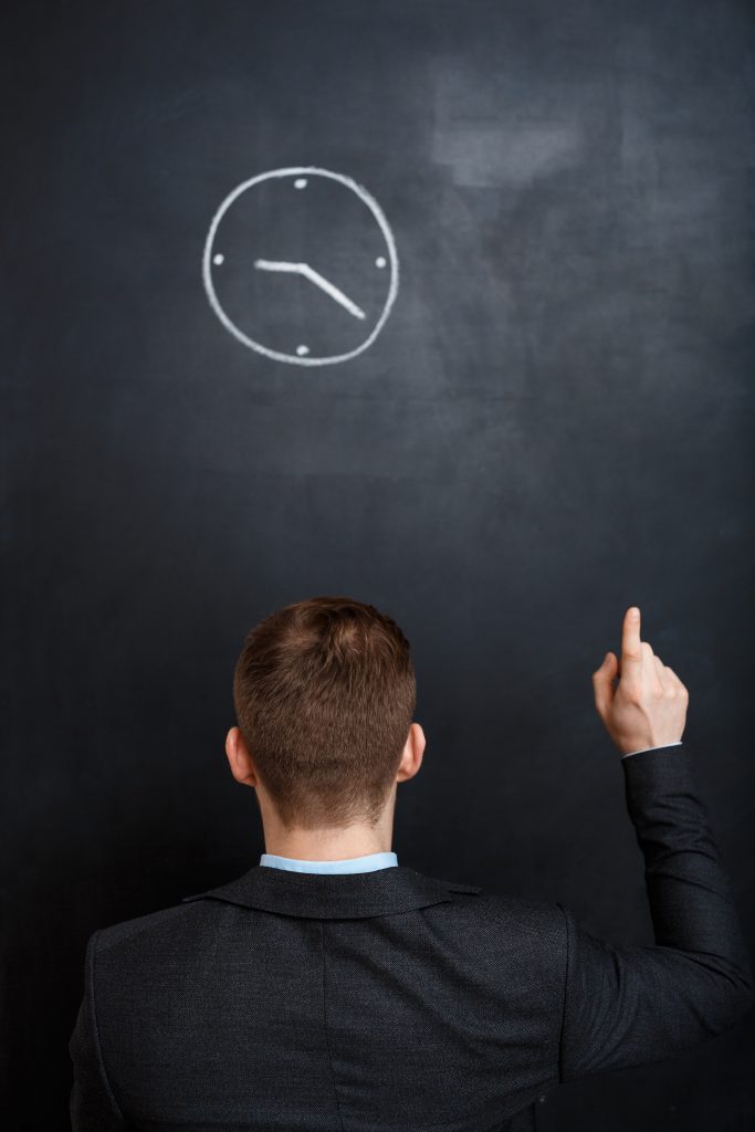 rear view of business man looking at clock. point with a finnger